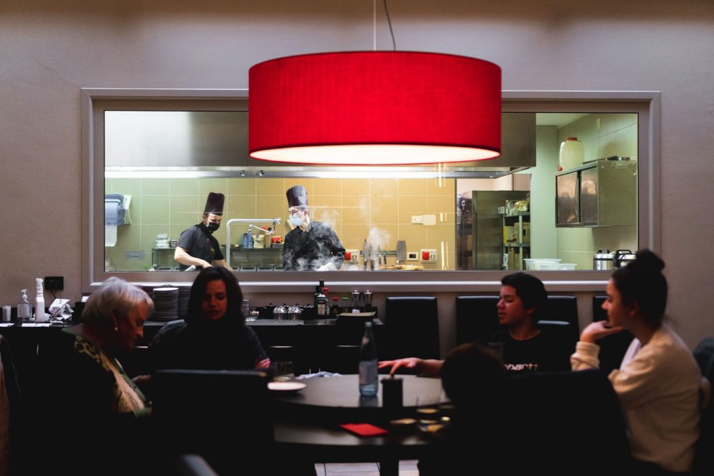 fooda_006 clienti seduti al tavolo del ristorante Fooda a Merano con vista sulla cucina a vista e cuochi orientali al lavoro