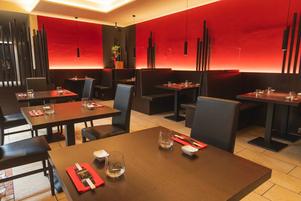 fooda_013 sala ristorante Fooda a Merano con tavoli apparecchiati in stile orientale e illuminazione calda