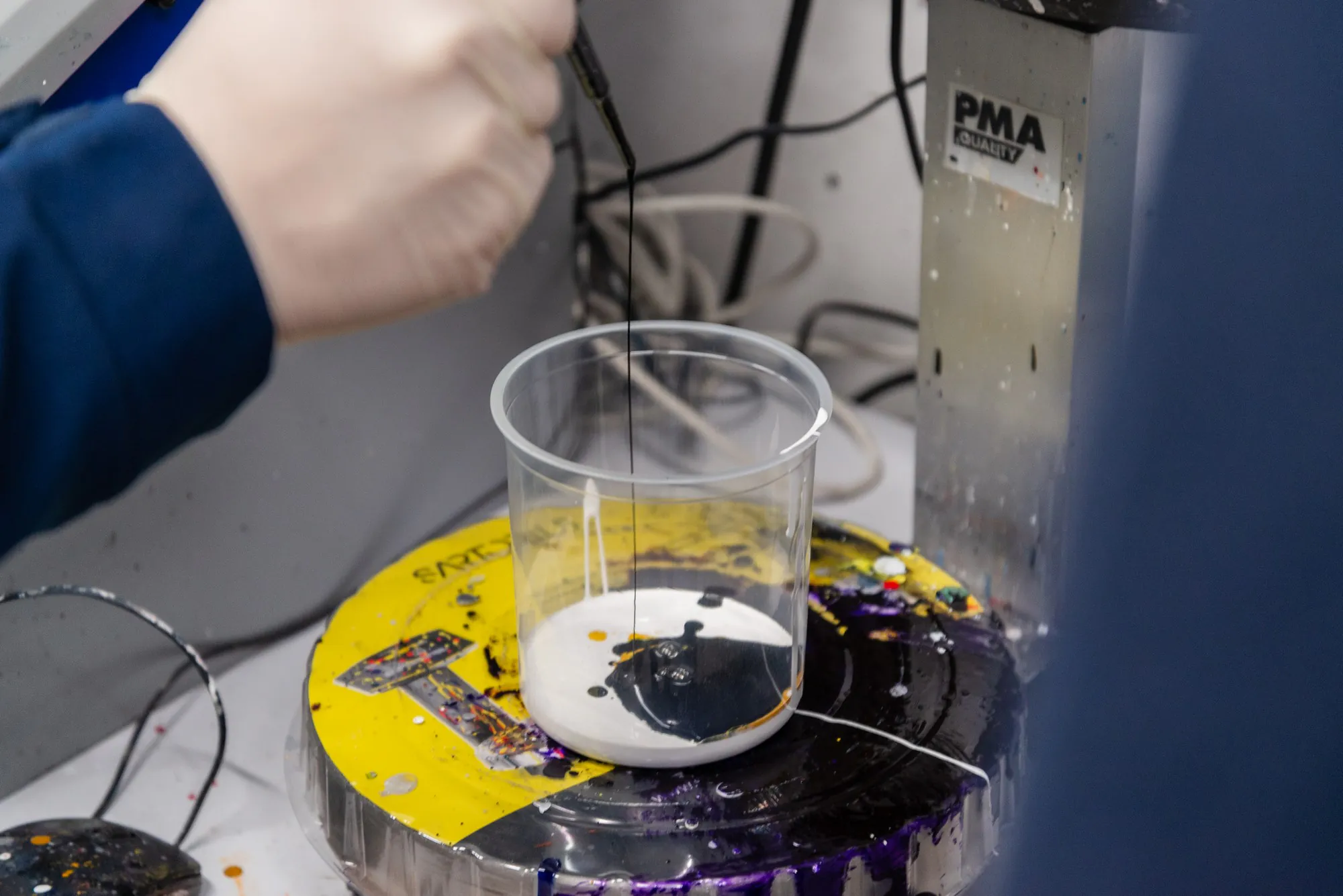 Preparazione di una miscela di vernice in laboratorio al Colorificio Bergamini a Bolzano, con pigmenti versati in un bicchiere graduato.