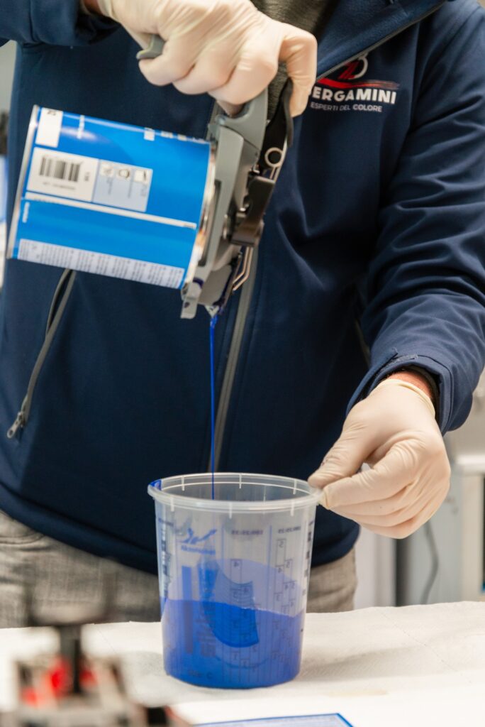 Tecnico del Colorificio Bergamini a Bolzano che dosa vernice blu in un bicchiere graduato