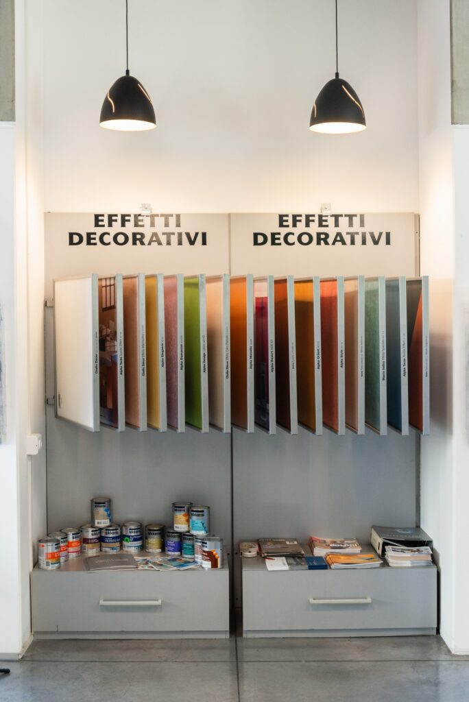 Espositore di effetti decorativi nel negozio del Colorificio Bergamini a Bolzano con campioni di finiture e barattoli di vernice