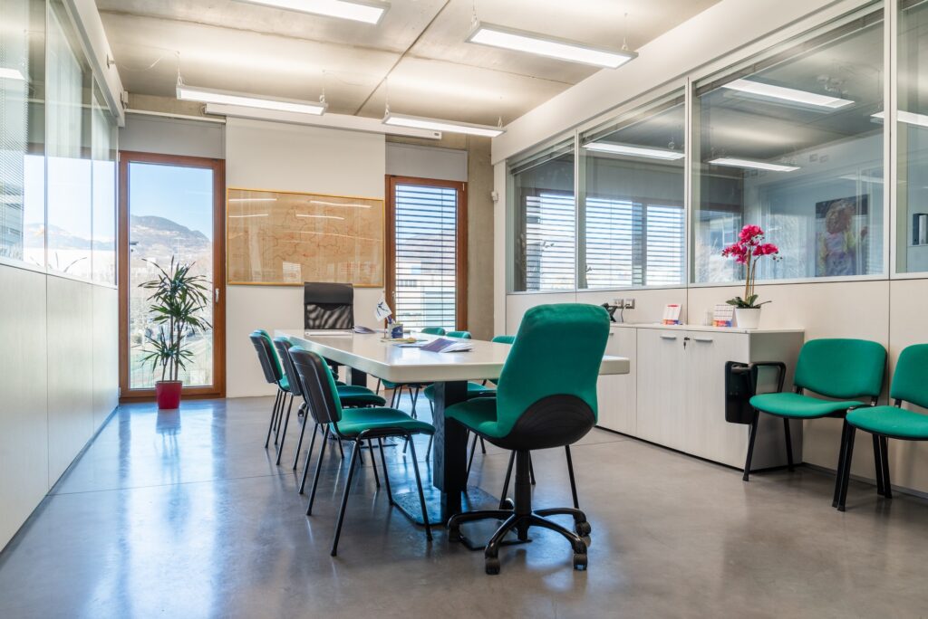 Sala riunioni luminosa e moderna del Colorificio Bergamini a Bolzano con tavolo centrale e sedie verdi